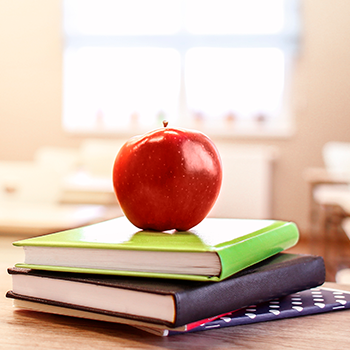 a red apple sitting on a stack of books