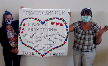 two teachers holding a sign with a heart on it