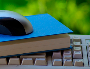 a book and a computer mouse and a book stacked on top of a keyboard